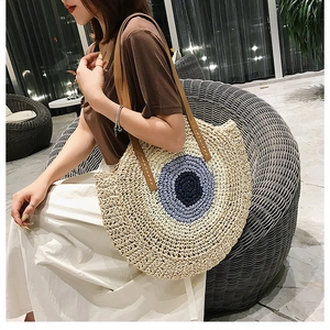Détail du sac cabas rond en paille avec motif œil et anses en cuir marron