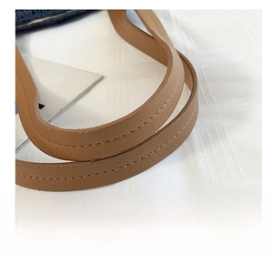 Gros plan sur l'anse en cuir marron clair avec des détails de double couture beige