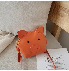 Detail of cute orange pig shaped mini crossbody bag with zipper on a soft sofa