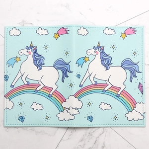 Light blue faux leather passport cover with cartoon unicorns and rainbows on marble