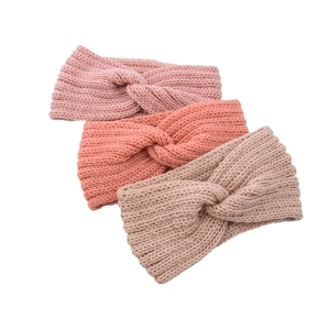 Close-up of three knitted cross-knot headbands in pink and brown with ribbed texture