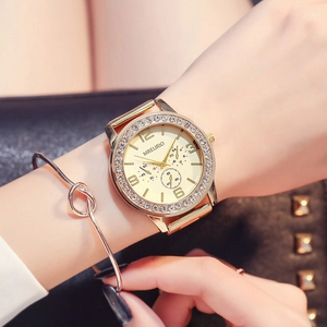 Women's gold quartz watch with rhinestone bezel and large dial on model's wrist
