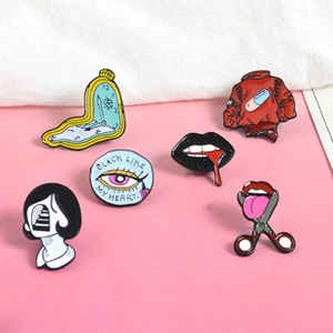 Collection of creative enamel pins featuring artistic motifs on a pink surface