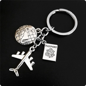 Detailed travel keychain with airplane, globe, and engraved passport charms on black background