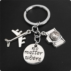 Detailed macro view of silver airplane, camera and no matter where charm keychain