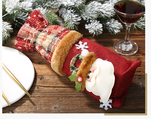 Detail of Christmas wine bottle cover with Santa Claus plush on red plaid burlap