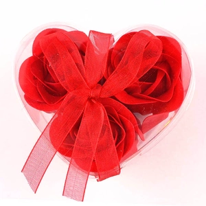 Three red soap roses in a heart-shaped transparent gift box with red ribbon bow