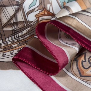 Macro detail of silk scarf showing hand-painted sailing boat pattern and rolled edges