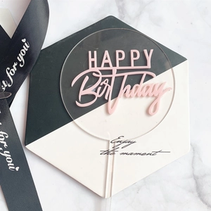 Detail of round acrylic Happy Birthday cake topper with pink lettering on hex stand