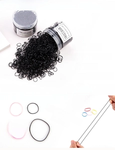 Détail d'élastiques à cheveux noirs et colorés dans une boîte de rangement transparente