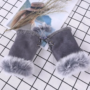 Close-up of grey fingerless gloves with fluffy faux fur trim and decorative pom poms