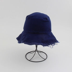 Detail view of frayed edges on dark blue canvas bucket hat on metal display stand