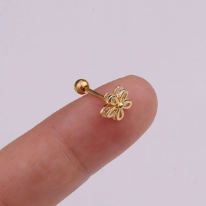 Detailed macro view of gold flower cartilage stud with cubic zirconia on a fingertip