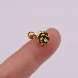 Close-up of golden rose ear stud with black enamel petals and sparkling zircon center