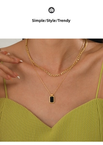 Close-up of double-layered gold necklace with black square pendant on a female model