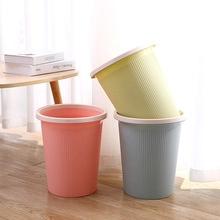 Three colorful textured plastic waste bins arranged on a wooden floor in a cozy home setting