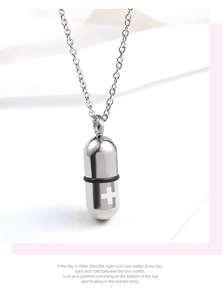 Macro detail of silver stainless steel capsule pendant with white cross and rubber seal