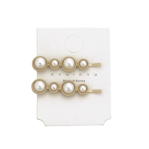 Detail showing two gold pearl hair clips with alternating beads on a display card
