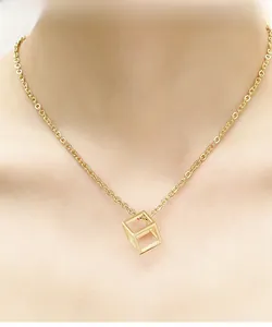 Close-up of a minimalist 18K gold hollow cube pendant necklace worn on the neck