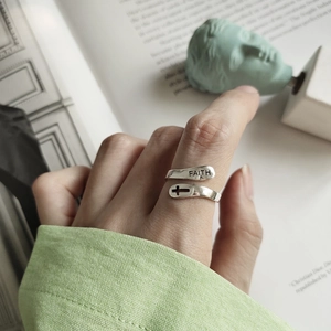 Detail of silver FAITH cross ring on model featuring minimalist engraved design