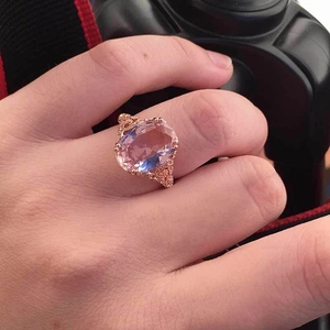 Detailed close-up of rose gold hollow ring with large oval pink gemstone on finger