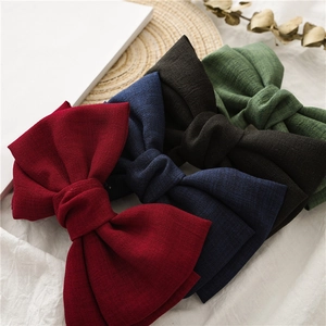 Close-up of textured fabric knotted bow hair clips in wine red, navy, black and forest green