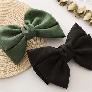 Close-up of knotted fabric bow hair clips in black and green checkered patterns