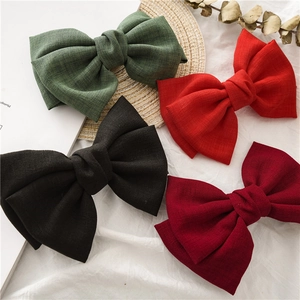 Close-up of four linen knot bow hair clips in green, red, black, and wine red