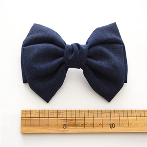 Dark blue knotted fabric bow hair clip shown on white background with 14cm scale ruler