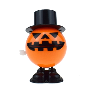 Close-up of orange Halloween pumpkin wind-up toy with black top hat and clockwork knob