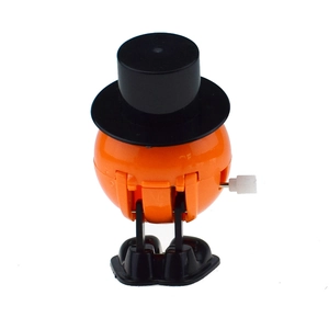 Detail of mechanical orange wind-up toy featuring a black top hat and side winding key