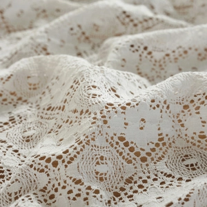 Macro detail of vintage white cotton lace tablecloth showing intricate floral crochet patterns