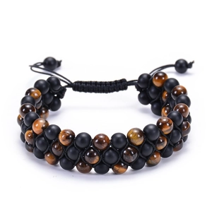 Detailed close-up of tiger eye and matte black beads in a triple-layer braided bracelet
