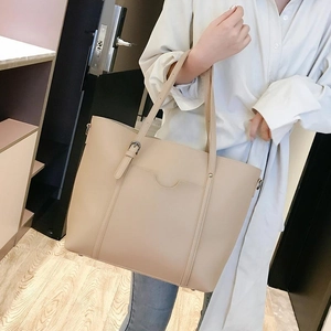 Detail of beige PU leather tote bag featuring adjustable straps and curved stitching accent