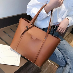Close-up of a brown PU leather tote bag worn by a model in a lifestyle setting