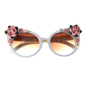 Detail of floral accents and gradient brown lenses on white cat-eye sunglasses