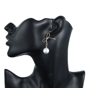 Detailansicht der eleganten goldenen Schleifen-Ohrringe mit weißen Perlen am Model