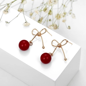 Elegante goldene Schleifenohrringe mit roten Kirschperlen auf weißem Display