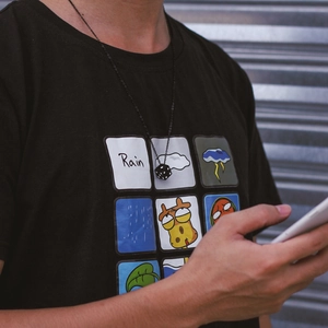 Minimalist black dice pendant necklace on a black chain worn with a casual streetwear outfit