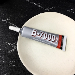 Macro view of B-7000 clear jewelry adhesive 25ml tube on a plate for rhinestone repair
