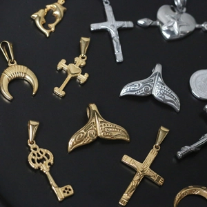 Detail of vintage 18K gold and silver steel pendants with cross and whale tail designs
