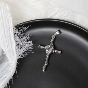 Detailed macro view of silver cross pendant with embossed rose and vine design