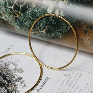 Polished 18K gold plated minimalist thin bangle displayed on a lifestyle magazine page