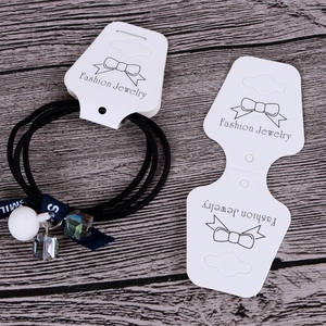 Detail of black elastic hair tie with cartoon rabbit pendant and crystal charms on display card