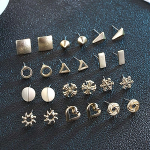 Macro view of assorted gold and bronze geometric stud earrings on a black texture