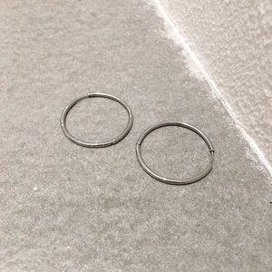 Close-up of minimalist silver round hoop earrings on a textured stone surface