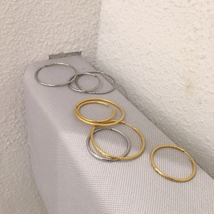 Classic gold and silver hoop earrings in multiple sizes on grey fabric background