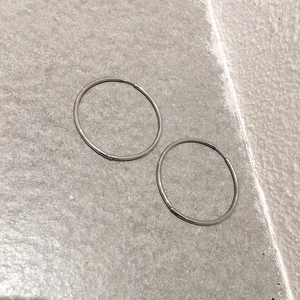 Macro view of silver minimalist large hoop earrings on a textured stone background surface