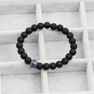 Detail of matte black beaded bracelet with blue tiger eye stone and crown charm