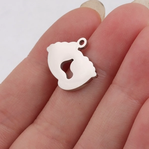 Macro view of baby feet stainless steel pendant held on finger to show compact size